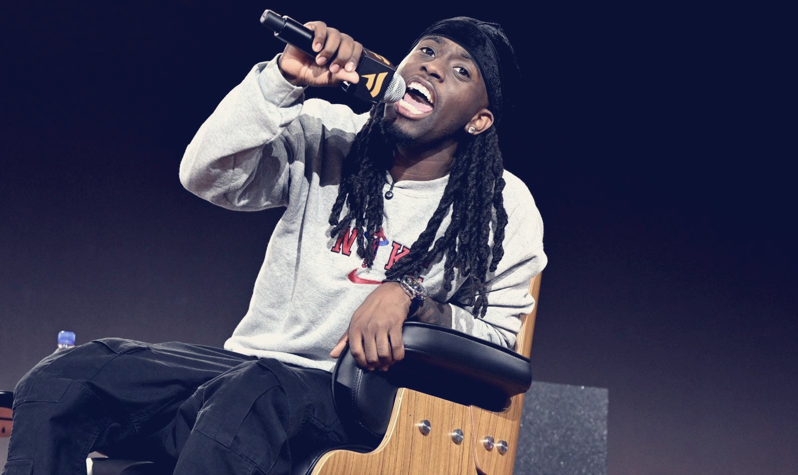Kai Cenat speaking onstage with a microphone at Fanatics Fest NYC, 2025