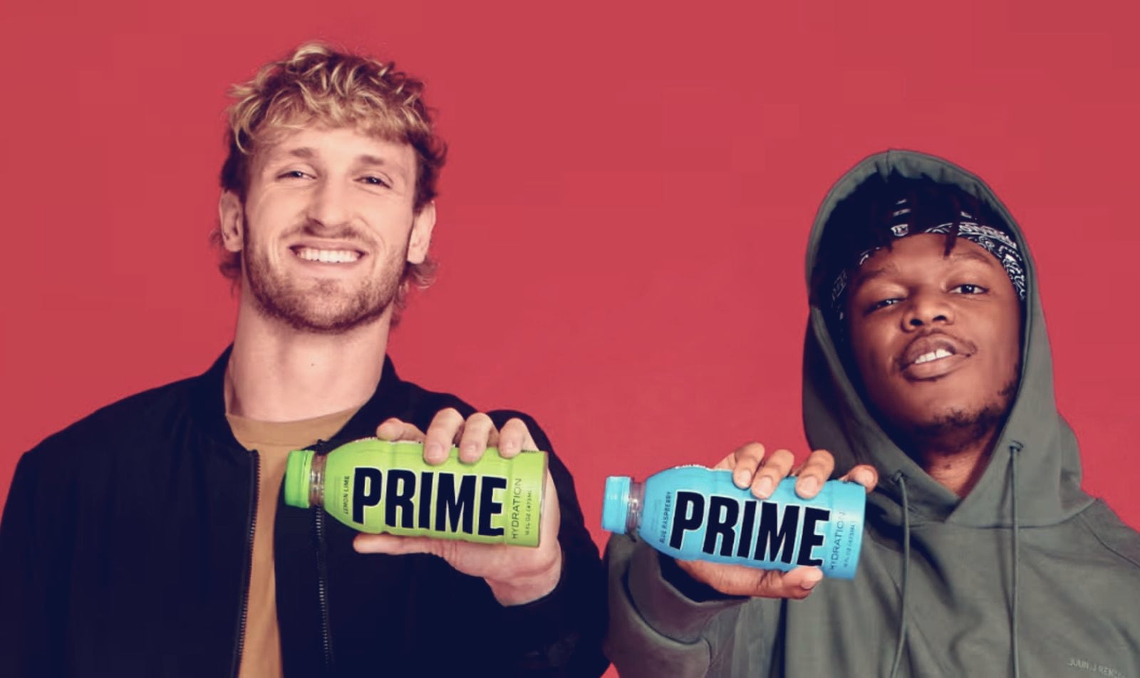 Logan Paul (left) and KSI, in jackets and a hoodie, holding Prime bottles against a red backdrop
