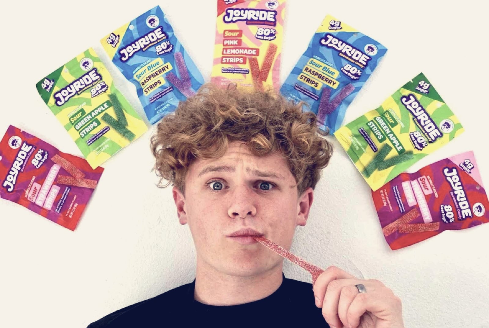 Ryan Trahan holding a Joyride candy strip with a fan of Joyride packs above his head, Joyride press photo, February 2024